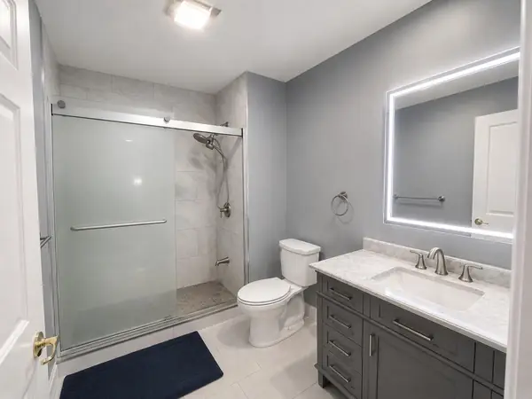 Renovated bath (2024) with walk-in glass shower and lit mirror